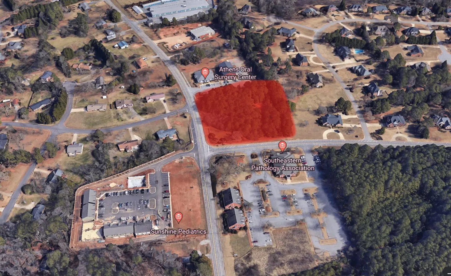 Aerial view of outlined commercial land parcel along a major roadway with surrounding medical and residential development